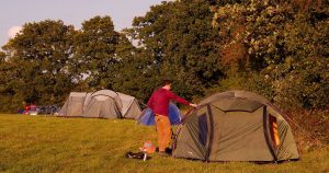 man setting up second tent on a campground site