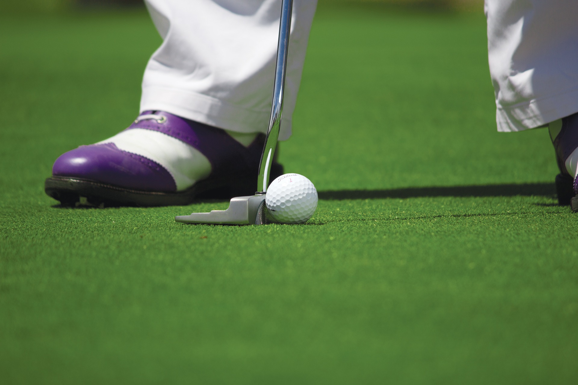 A man standing on a putting green, preparing to putt his ball